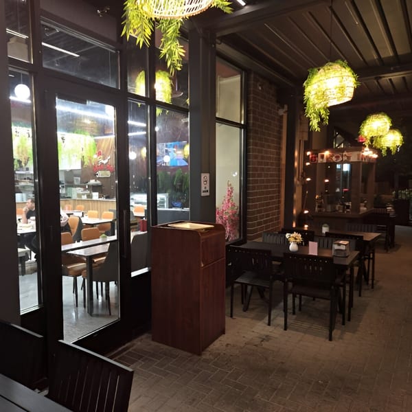 Baba Saj's outdoor patio with dark tables and chairs, illuminated by hanging green plant lights.