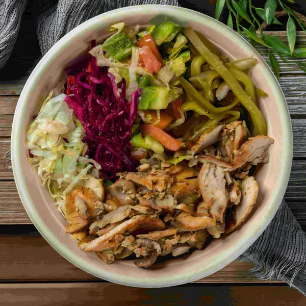 A Baba Saj Mediterranean chicken shawarma bowl with shredded chicken, red cabbage, lettuce, and pickled vegetables.
