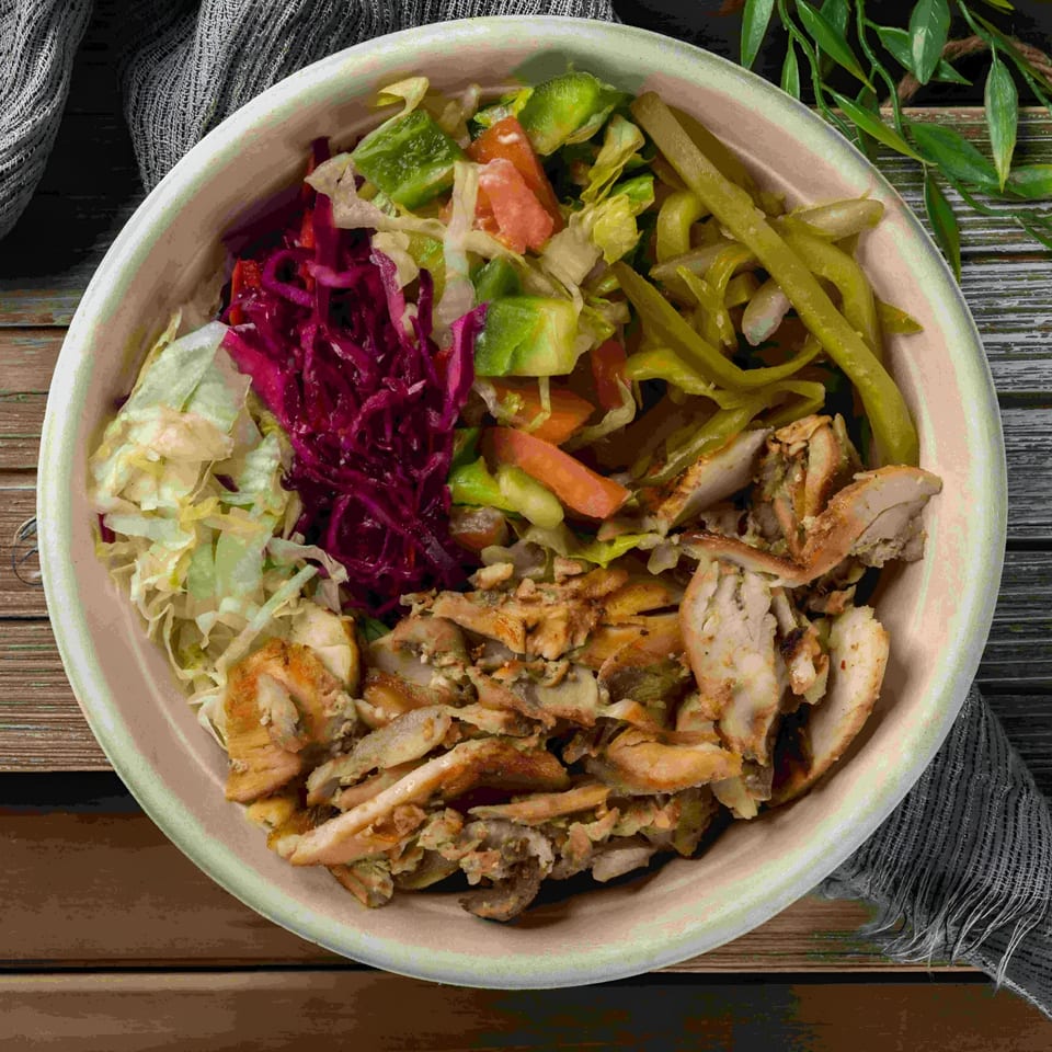 A Baba Saj Mediterranean chicken shawarma bowl with shredded chicken, red cabbage, lettuce, and pickled vegetables.