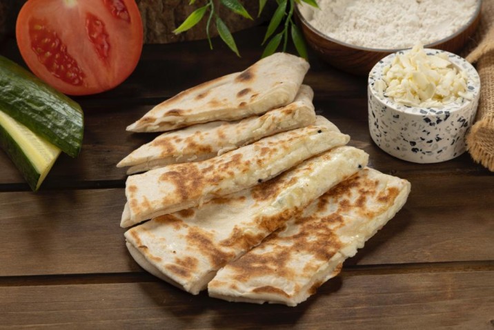 Delightful quesadillas on rustic wood table with fresh tomato and cucumber make a delicious appetizer or light meal with savory cheese filling